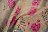 Folded vintage distressed Oushak rug showing large magenta blossoms, ivory, dusty green, and nuanced texture.