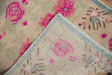 Folded corner of a distressed Oushak rug, revealing hand-knotted construction and pale blue selvage.