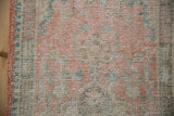 Distressed vintage Oushak rug pile showing pale tangerine, ivory, seafoam, and side cord.