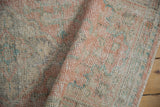 Distressed Oushak runner pile, showcasing visible knot heads and muted tangerine, ivory, and seafoam hues.
