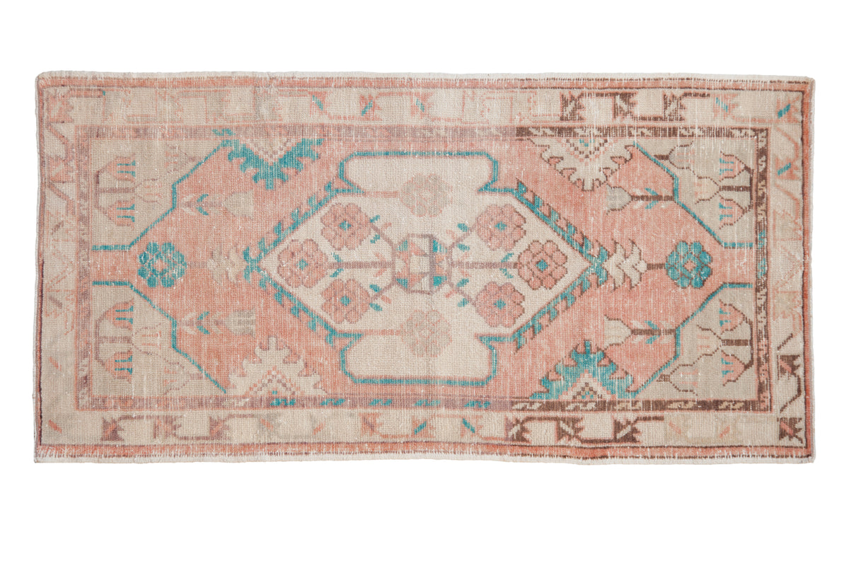 Distressed vintage Oushak rug with a shield medallion and floral motifs in pale melon, ivory, and bright turquoise.