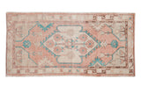 Distressed vintage Oushak rug with a shield medallion and floral motifs in pale melon, ivory, and bright turquoise.