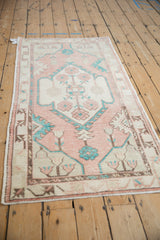 Distressed vintage Oushak rug seen from an angle, showing its soft cantaloupe and turquoise medallion.