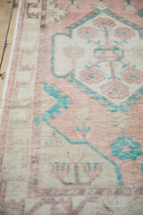 Angled view of a distressed Oushak rug, showing the low-pile texture in cantaloupe, ivory, and turquoise.