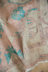Hand-knotted texture of a distressed Oushak rug with low pile in cantaloupe, ivory, and turquoise.
