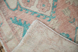 A distressed Oushak rug's corner folded to show the low pile and hand-knotted foundation.