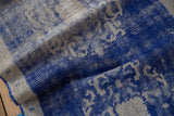 Distressed Oushak rug showing worn cobalt blue pile, revealing platinum foundation with squared motifs.