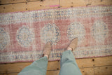 Distressed Oushak runner with worn pile, blush, cobalt, ivory scalloped medallions.