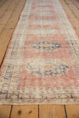 Angled view of Vintage Distressed Oushak runner, showing time-softened blush medallions and pawn borders.