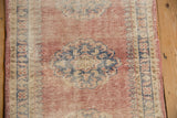 Distressed Oushak runner's worn blush pile, displaying cobalt blue pawn motif and intact selvage.