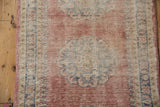 Oushak rug close-up: distressed blush pile, pawn motif border, and intact selvage.