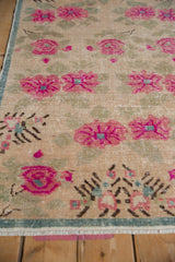 Distressed vintage Oushak runner pile featuring fuchsia floral motifs and pale green leaves.