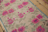 Distressed Oushak rug's fuchsia floral blossoms and pale green finned leaves, showing pile wear.