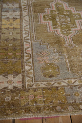 Vintage Distressed Oushak rug's muted geometric pattern in olive green and dusty rose.