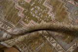 Textured pile of a vintage distressed Oushak rug, showing olive green and pink geometric details.