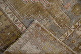 Folded corner of a distressed Oushak rug showing hand-knotted foundation and worn olive pile.
