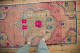 Distressed pile texture showing starburst floral motifs in fuchsia, teal, and pink.