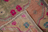 Distressed Oushak runner corner, revealing fuchsia flowers, worn pile, and visible foundation.