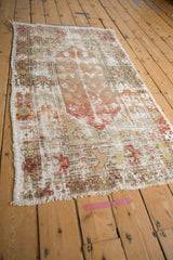 Distressed Oushak rug's worn pile, exposed foundation, colorful stylized motifs, and fringed edge.