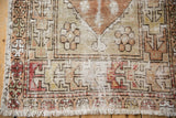 Oushak rug corner revealing distressed pile, foundation wear, and muted red, sand patterns.
