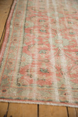 Side view of vintage distressed Oushak runner, highlighting worn blush and mint floral motifs.