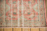 Distressed Oushak rug's textured pile: blush, mint, ivory, worn Herati pattern, fringe.