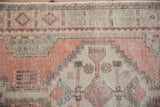 Distressed vintage Oushak rug detail: cantaloupe, mint, ivory geometric patterns, with even pile wear.