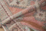Distressed Oushak runner pile, showing soft rose, mint green, and ivory geometric patterns.