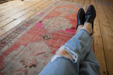 Distressed Oushak runner, madder red, fuchsia, beige medallion with worn texture.