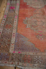 Distressed vintage Oushak runner with worn rust field, intricate geometric and floral border, magenta accents.