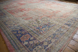 Distressed vintage Oushak rug, showing muted red and blue floral patterns and worn foundation.