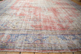 Distressed Oushak carpet texture revealing worn pile and faded cherry red, denim blue.