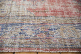Distressed Oushak rug detail showing worn pile, exposed foundation, and muted red and blue tones.