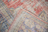Worn pile of distressed Oushak rug with visible foundation, muted red, blue, ivory.