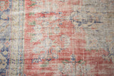 Distressed Oushak rug section with worn cherry red pile and denim blue border elements.
