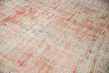 Close-up of distressed Oushak rug, faded rose and ivory pile with visible foundation.