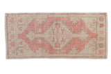 Hand-knotted vintage distressed Oushak mat runner, dusty rose and ivory geometric medallion.