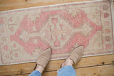 Distressed vintage Oushak rug with stepped geometric medallion and dusty rose, ivory, beige tones.