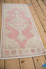 Distressed vintage Oushak rug corner in pink and ivory, showing even wear and faint foundation.