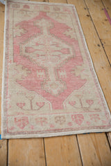 Distressed vintage Oushak rug corner with dusty rose, ivory stepped geometric and floral motifs.