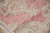 Distressed vintage Oushak rug, close-up of faded pink geometric pattern with faint foundation.