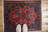 A scale view of the vintage Mehreban square rug, showing the rich raspberry and sapphire blue floral pattern.