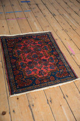 Angled view of a vintage Mehreban rug with a floral pattern in raspberry and sapphire blue.