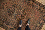 Antique Farahan Sarouk rug detail: hexagonal medallion, Herati motif, botehs, and time-softened palette, viewed with feet.