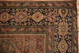 Corner of an antique Farahan Sarouk rug with classic floral vinery and a soft, aged pile.