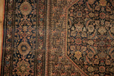 Antique Farahan Sarouk rug: detailed navy field of botehs meeting a classic floral border.