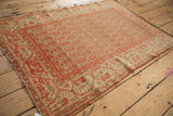 Distressed vintage Malayer rug corner showing time-softened cinnabar red and neutral patterns.