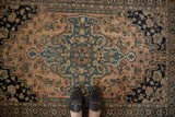 Patinaed antique Farahan Sarouk rug with dusty blush field and blue medallion.