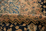 Folded detail of an antique Persian Farahan Sarouk rug, revealing worn blush pile and navy zigzag border.