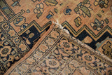Close-up of folded antique Farahan Sarouk rug, showing worn pile and intricate hand-knotted foundation.